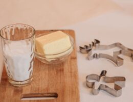 Smör i en glasskål bredvid mjöl och kakformar på en skärbräda