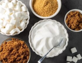 Skålar med strösocker, farinsocker och vita sockerbitar för bakning