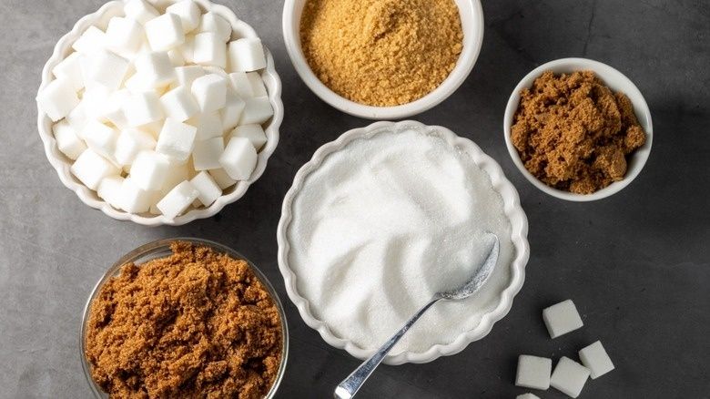 Skålar med strösocker, farinsocker och vita sockerbitar för bakning